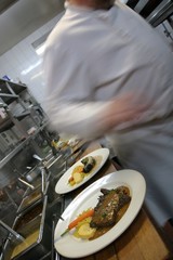 Cook is preparing main courses in kitchen of a restaurant