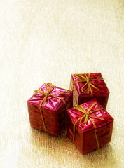 Three red gift boxes on golden background & free space for text