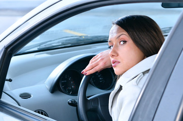 beautiful sensual woman put her head on steering wheel and looki