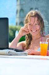 beautiful woman is using laptop in the swimming pool