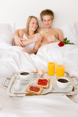 Obraz na płótnie Canvas Luxury hotel honeymoon breakfast - couple in bed