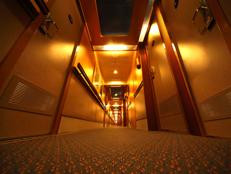 Narrow And Illuminated Corridor With Hotel Rooms In Cruise Ship