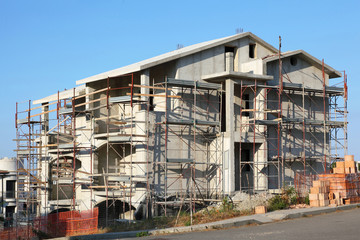 Building of new three-storeyed cottage near road in resort town