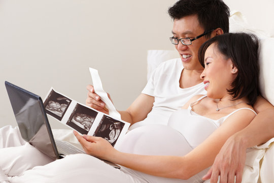 Asian male making coffee couple looking  at USG print on bed