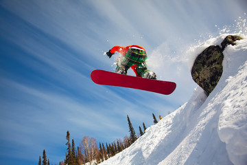 Snowboarder jumping through air with  blue sky in background