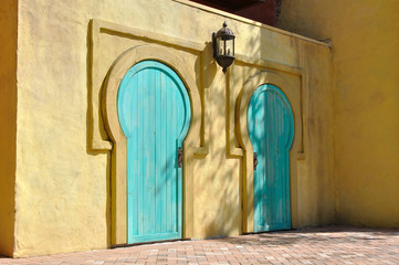 Side view of a pair of african style doors on a yellow house