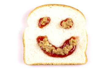 Happy face peanut butter and jelly on white bread on a white bac
