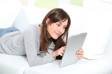 Young woman sitting on sofa with electronic pad