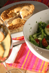 Meat pie with white wine and salad in sunlight, in Quebec a traditional meal called 