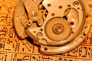 Fototapeta na wymiar Antique watch mechanism on Egyptian text background