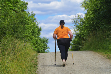 Übergewichtige Frau beim Nordic Walking, Rückansicht
