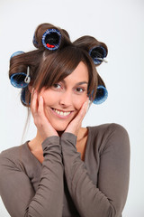 Beautiful woman with hair-curlers doing funny faces
