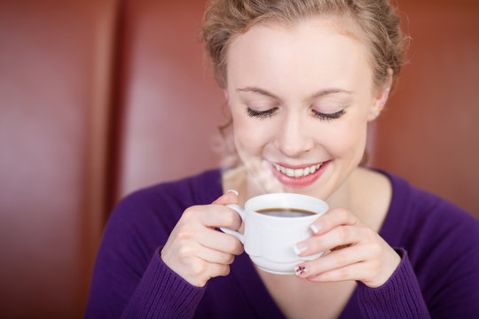 lächelnde frau trinkt dampfenden kaffee