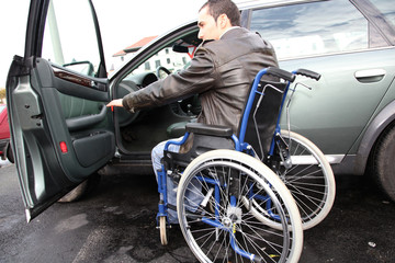 Obraz na płótnie Canvas Young man in wheelchair getting in his car