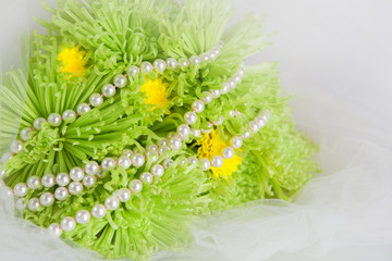 White necklace of pearls and bouquet of chrysanthemums on a whit