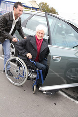 Fototapeta na wymiar Young man assisting senior woman in wheelchair