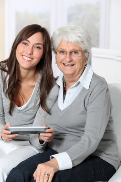Young woman playing video game with grandmother