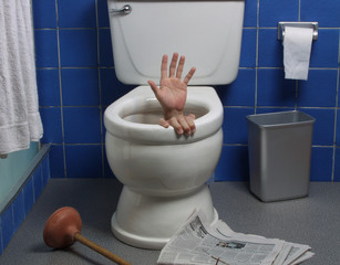 Hand reaches up through the seat from out of a toilet.