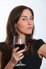 Beautiful woman in black dress tasting red wine
