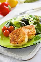 Two potato cakes on a plate with fresh green salad