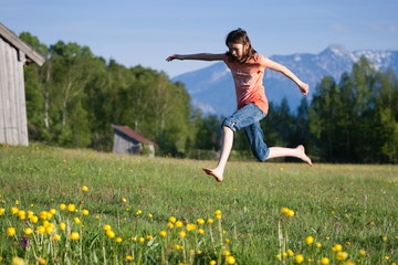 Mädchen springt auf Blumenwiese