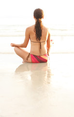 Young woman meditating near ocean