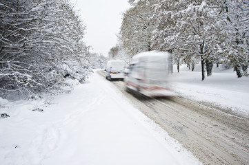 Road in deep Winter snow with blurred moving cars