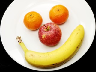 4 fruits on white plate, towards dark background