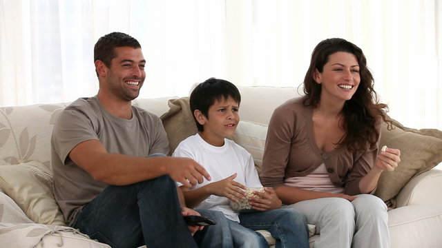 Family eating pop corn while watching television at home