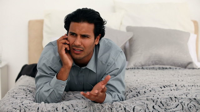 Man talking on the phone on the bed