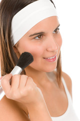 Skin care - young woman apply powder with make-up brush