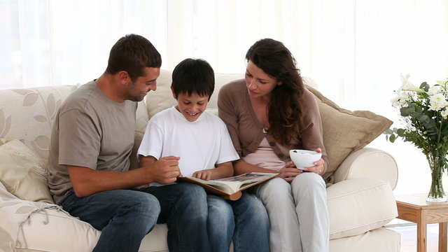 Cute family looking at a photo album together on the sofa