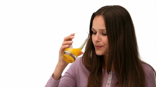 Cute girl drinking an orange juice against a  white background
