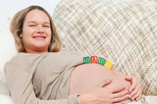 Portrait of a happy future mother with baby letters on her belly