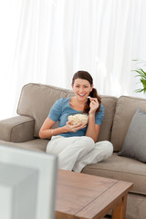 Woman laughing while watching a movie on television in the livin
