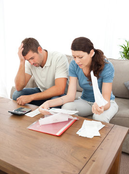 Worried couple looking at their bills in the living room