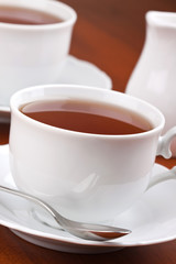Black tea in mugs with saucers