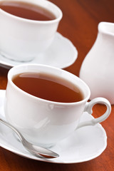 Black tea in mugs with saucers