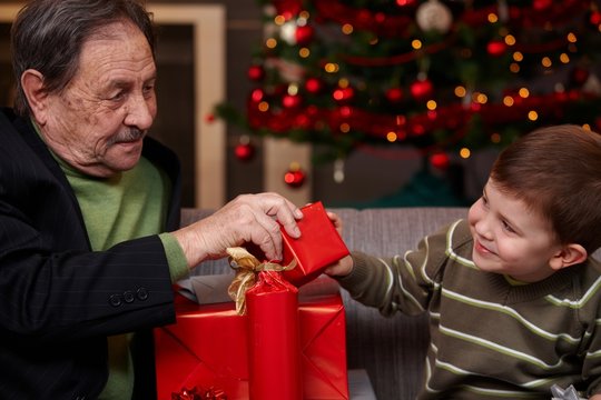 Grandchild giving christmas present to grandfather