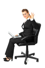 Smiling modern business woman with laptop showing ok gesture