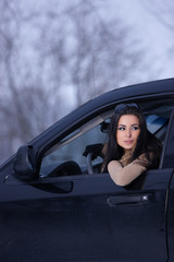 Beautiful woman in car in snowy winter outdoors