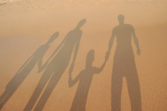 Family shadows on beach sand