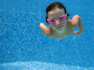 Naklejka premium Child swimming underwater in the pool