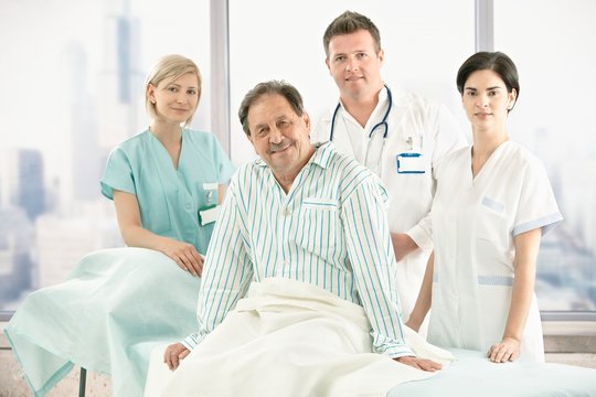 Older patient on bed with hospital crew