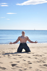 Fototapeta na wymiar Muscular man kneel on beach and screaming