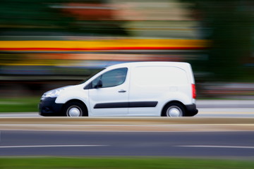Speedy  white minivan  is  going on road, panning and blur