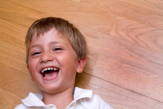 bambino che ride sdraiato sul parquet