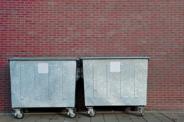 garbage containers in front of brick wall