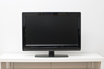 Black flat screen tv set on white table and wall