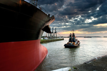 Tug boat taking out the ship from the harbor - obrazy, fototapety, plakaty